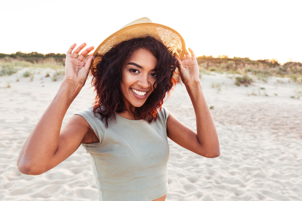 Woman with long hair wearing a hat on the beach