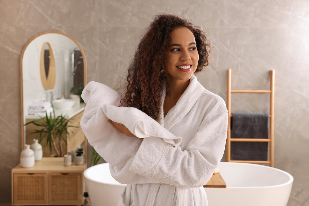 woman with curly hair towel drying her hair in bathroom